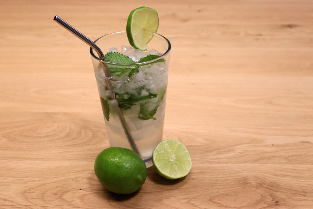 Sommergetränk: Mojito in einem hohen Glas, verziert mit Minze und Limetten